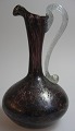 Italian glass 
jug, 20th 
century in 
brownish glass 
with clear 
glass handle. 
H.: 14.5 cm.