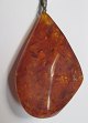 Large polished 
piece of amber 
with seed 
capsules. With 
silver pendant. 
L .: 5.5 cm. B 
.: 3.5 cm.