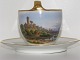 Royal 
Copenhagen 
large high 
handle cup 
decorated with 
"Gaase Taarnet" 
and with people 
and ...