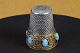 Thimble in 
silver 
decorated with 
gilding and 
tyrkis. Stamped 
800 S. art. No. 
116