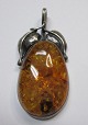 Polished amber 
pendant with 
silver mounts, 
20th century. 
With seed 
capsules. 
Stamped: 925 
for ...