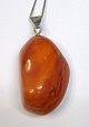 Large polished 
amber piece, 
milk amber, 
Denmark. With 
pendant and 
chain in 
silver. Length: 
4 cm.
