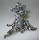 Silver table 
card, 20th 
century. Rococo 
style, 
decorated with 
angel. 6 x 7 
cm. Stamped: 
830. ...