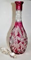 Bohemian 
crystal carafe 
with stopper, 
20th century. 
Red overlay 
with grindings. 
Height: 40.5 
cm.