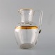 Baccarat, 
France. Art 
deco jug in 
mouth-blown 
crystal glass 
with gold 
decoration in 
the form of ...