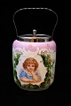 Old biscuit jar 
in painted opal 
glass with lid 
/ handle in 
metal, 
decorated with 
a girl's ...