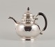 Rare Georg 
Jensen teapot 
in 
three-towered 
silver (830).
Handle and lid 
knob of carved 
ebony. ...