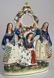 Staffordshire 
clock keeper 
with three 
women. Polycrom 
decoration, 
approx. 1830 - 
1840. Faience. 
...