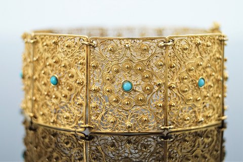 A wide filigree bracelet of 18k gold set with turquoises