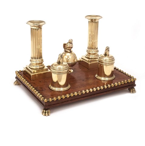 Writing set on a mahogany base with a pair of 
brass candlesticks, small sand- and ink containers 
and a bell. Circa 1780. Base: 19x25,5cm. H: 17cm