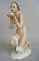 Porcelain 
figurine of a 
seated naked 
woman with 
drinking cup, 
cold painted, 
20th century. 
...