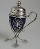 Mustard pot of 
silver with 
blue glass 
insert. Body 
with lion feet 
and 
filigree&nbsp;work.
 Domed ...