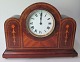 Mantel clock 
app. 1920. 
Mahogany with 
intarsia. 
French work. 
B.: 27 cm. H.: 
20 cm.