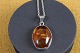Pendant of 
polished 
cabochon cut 
amber mounted 
in silver frame 
with lace edge 
and 
corresponding 
...