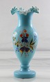 Hvid opal vase 
med blå 
overfangsglas. 
Blondekant. 
Vasen er 
bemalet med 
blomstermønster.

Højde ...