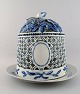 Antik Royal Copenhagen isklokke på fad af porcelæn, musselmalet, dekoreret i blå 
underglasur, gennembrudt klokke med stiliseret bladværk.