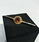 Brooch in 14 
ct. gold with 
amber colored 
stone.
5,5x1,3 cm.