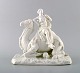 Sjælden Royal Copenhagen kontinent-serie, Afrika blanc de chine figur i form af 
en kvinde siddende på en kamel. Sent 1800-tallet.