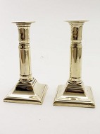 A pair of brass empire telescope candlesticks sold