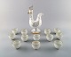 Bing & Grondahl/ B&G, Denmark. Jug of porcelain in the form of rooster, stopper 
with rooster comb. 12 accompanying porcelain mugs with gold-painted details.