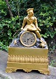 French gilded fireplace clock, 1810 - 1830. Decoration in the form of boy with ring. H: 40 cm. B ...