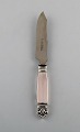 Georg Jensen 
"Acanthus" 
cheese knife in 
silver, blade 
in steel. 
Dated 1923.
Designer: 
Johan ...