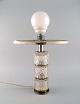 Scandinavian 
designer table 
lamp in steel 
and art glass. 
Mid-20th 
century.
Measures: 30 x 
9 cm ...