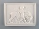 Bing and Grøndahl after Thorvaldsen. Antique biscuit wall plaque with puti and 
lion in relief. 1870 / 80s.
