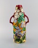 Stor antik art nouveau vase med hanke i glaseret keramik. Håndmalede blomster og 
bladværk på rød baggrund. Tidligt 1900-tallet.
