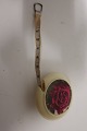 Measuring tool in a round holder, the holder is 
with a rose decorated
The measuring tape is pulled out from the box and 
let in again
Text: "Dean Measure" Made in England