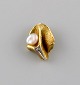 Scandinavian jeweler. Organically shaped pendant in 14 carat gold adorned with 
cultured pearl and semi-precious stone.
