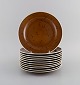 Stig Lindberg for Gustavsberg. 11 Coq frokosttallerkener i glaseret stentøj. 
Smuk glasur i brune nuancer. Svensk design, 1960