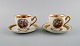Two Royal Copenhagen coffee cups with saucers decorated with flowers and 
romantic scenes. Gold decoration. Mid-20th century.
