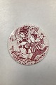 Red monthly plate in faience for August  "BYE-BYE". Designed by Bjørn Wiinblad for Nymølle. In ...