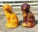 Figur af hund i keramik som sparebøsse. Én i lys gul glasur og én i brun glasur. Fremstillet i ...