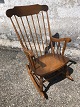 Older rocking 
chair in dark 
stained wood 
with 
embroidered 
cushions.