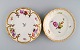 KPM, Berlin. To antikke tallerkener i svejfet porcelæn med håndmalede blomster 
og gulddekoration. Sent 1800-tallet.

