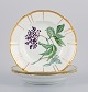 Bing and Grøndahl, three deep porcelain plates in Flora Danica style with gold 
decoration.