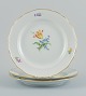 Meissen, Germany. Three large dinner plates in porcelain hand-painted with 
various floral motifs and gold rim.