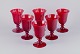 A set of six large wine glasses in red glass.