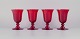 A set of four large red wine glasses.