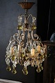 Decorative, old French chandelier with clear glass prisms and glass balls in a delicate yellow ...