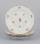 Meissen, Germany. A set of four dinner plates in porcelain, hand-painted with 
different polychrome flower motifs and a gold rim.