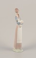 Lladro, Spain. Porcelain figurine of a standing young woman holding a lamb in her ...