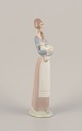 Lladro, Spain. 
Porcelain 
figurine of a 
standing young 
woman holding a 
lamb in her ...