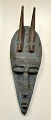 African mask, mid 20th century. Carved wood with beaten blue painted metal. With two horns. H.: ...