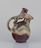 Bode Willumsen 
for Royal 
Copenhagen. 
Ceramic pitcher 
in sung glaze. 
Handle in the 
shape of a ...