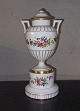 Urn vase cup 
with lid in 
porcelain 
standing on 
plinth. Painted 
with flowers. 
Manufactured at 
the ...