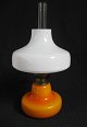 Holmegård Glass oil lamp, 1960s. In orange glass with white cover. Burner in brass. H.: 30 cm. ...