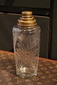 Nice old 
cocktail shaker 
in glass with 
beautiful 
floral cuts 
and brass top. 
H: 22cm.